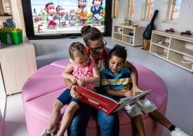 A mother with her two kids reading a book at Ronald McDonald house Charities.